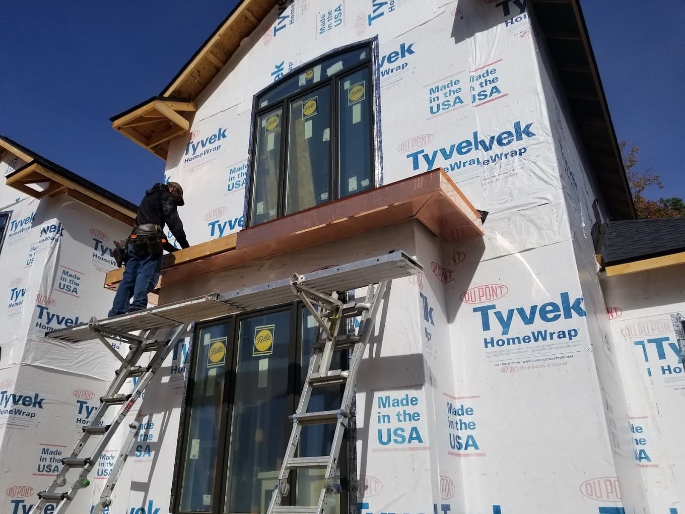 Estepp & Son crew member on scaffolding fitting a copper roof over a bay window on a new home