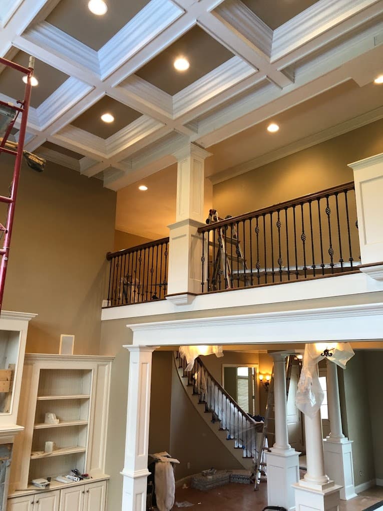 Two-story great room with a coffered ceiling, columns and an iron balcony railing