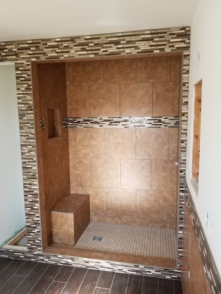 Walk-in tile shower with a built-in bench, wall niche and mosaic tile border