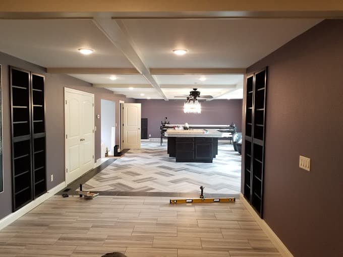 Renovated basement with herringbone tile floor, built-in shelving and a kitchen island