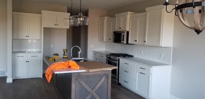 White shaker kitchen with a patterned tile backsplash and a gray island